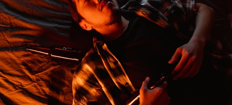 Man lying on the bed next to a beer bottle after mixing alcohol with drugs.
