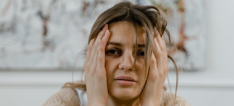 Woman holding her head while thinking about using self-medication for bipolar disorder.
