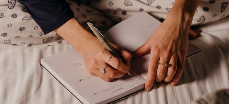 Woman journaling while sitting on the bed.