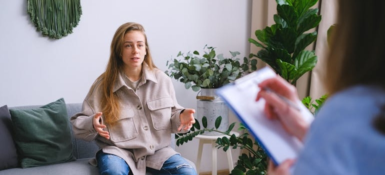 Doctor writing in a clipboard while talking to a patient.
