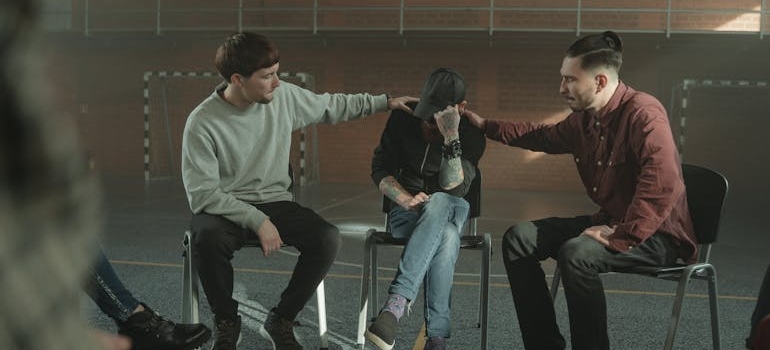 People in group therapy supporting a man while talking about the fentanyl abuse signs.