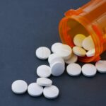 White pills spilling out of an orange pill bottle.