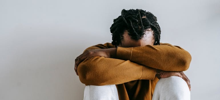 Depressed man sitting on the floor with his head in his arms.