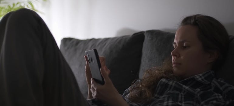 Woman reading about the benefits of a digital detox during addiction recovery on her phone.