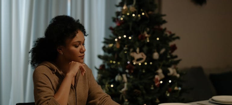 Woman sitting at the dinner table with a Christmas tree behind her.