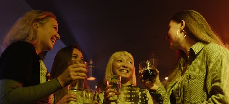 Four friends standing in a party and drinking alcohol.