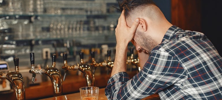 Stressed out man sitting at a bar and having a drink.