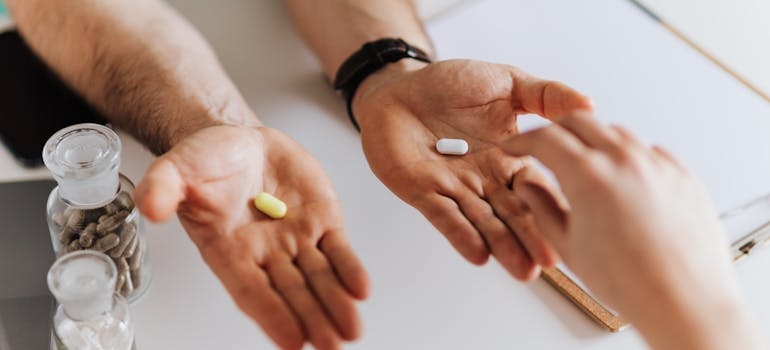 Doctor handing out two different pills in his hands.