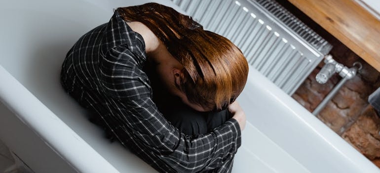 Woman sitting in a filled bathtub while still in clothes.