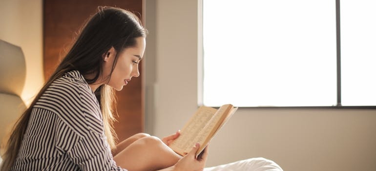 Woman reading a book in bed while practicing digital detox during addiction recovery.