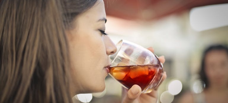 Woman drinking a cocktail while hanging out with friends.