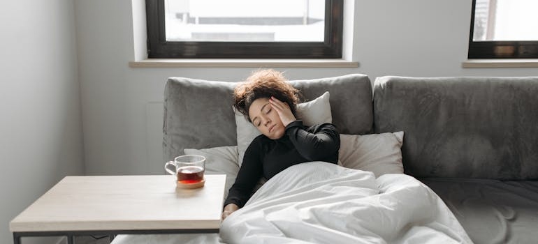 Woman lying in bed with a headache and rubbing her temples.