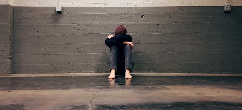 Man sitting on the floor with his head in his hands.