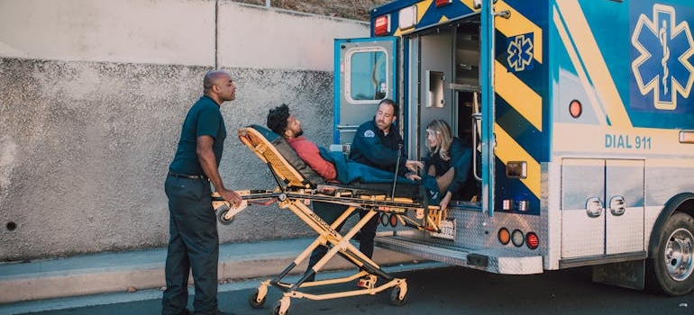 Paramedics wheeling a man into an ambulance.