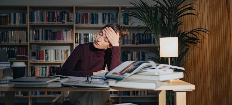 Tired woman surrounded by books while studying.