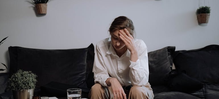 Woman sitting on the couch and rubbing her forehead.