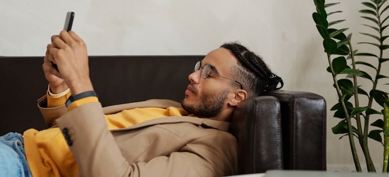 Man lying on the couch and holding his phone.