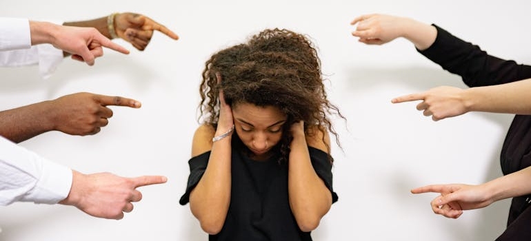 Stressed woman being pointed at by many people.