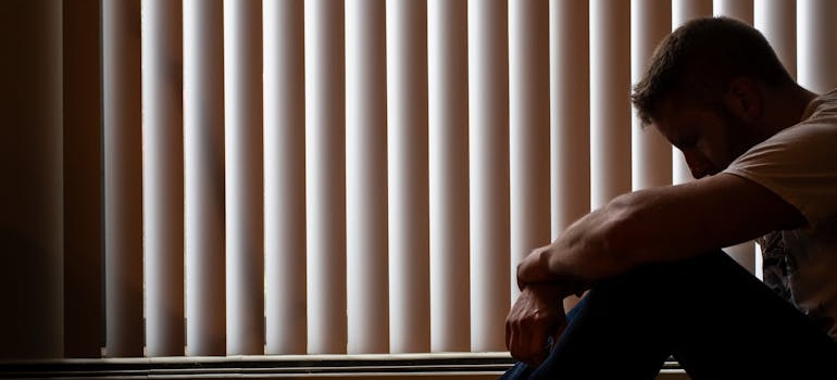 Man sitting near a closed window.