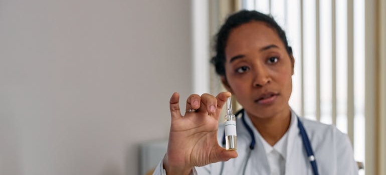 Doctor holding a vial of medication while talking with a patient.