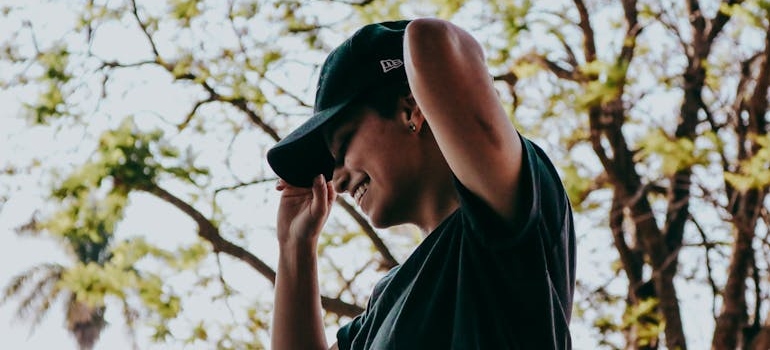 Woman smiling while putting on a baseball cap.