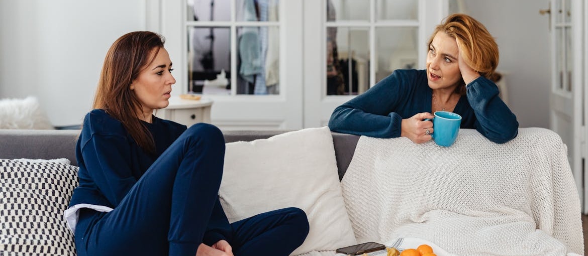 Two women sitting on the couch and having a conversation about their social life after rehab.