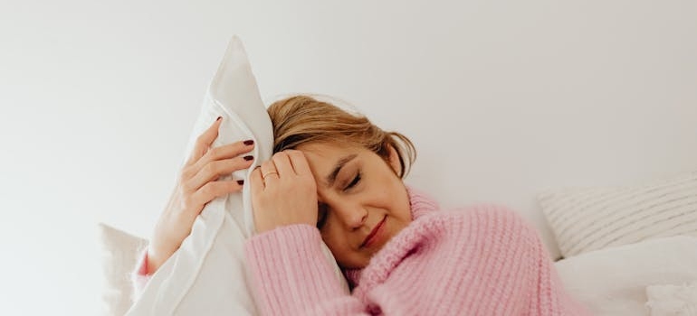 Tired woman hugging a white pillow.
