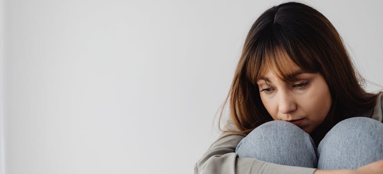 Woman sitting on the floor and hugging her knees.