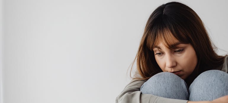 Upset woman sitting on the ground and hugging her knees.