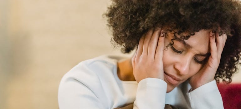 Stressed woman holding her head while worrying about her issues with morphine addiction.