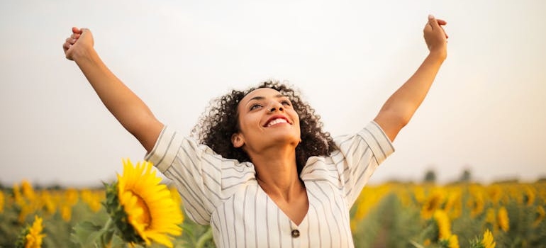 Woman lifting her arms while looking at the sun.