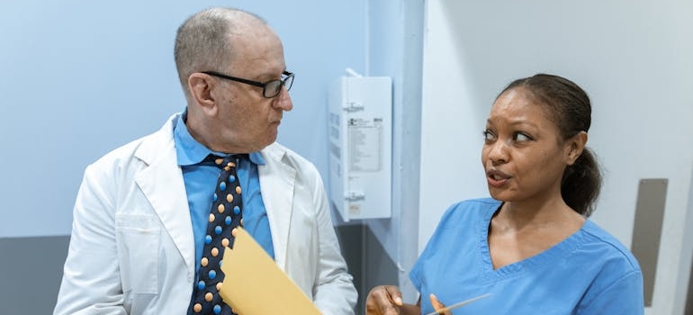 Doctor and nurse standing in a hospital hall and talking with each other.
