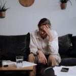 Worried woman sitting on the couch and looking at the floor.