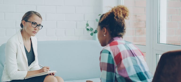 Woman writing in a clipboard while doing a polysubstance addiction assessment on a patient.