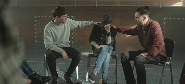 Men comforting a friend in a peer support group.