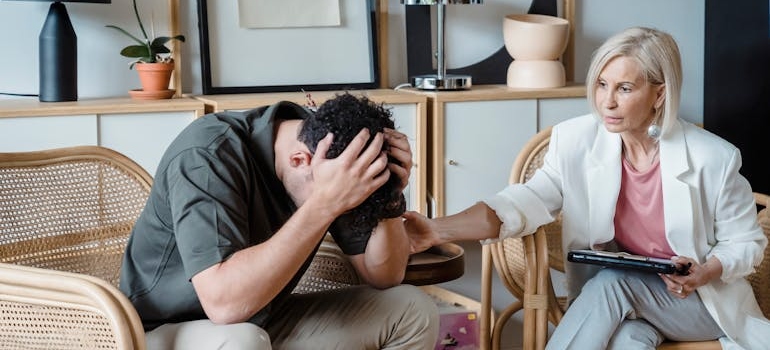 Therapist comforting an upset patient and suggesting staying longer than 30 days in rehab.