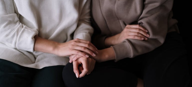 Two girls sitting next to each other and holding hands.