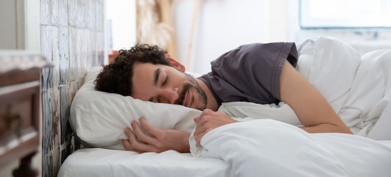 Man hugging his pillow while lying in bed.