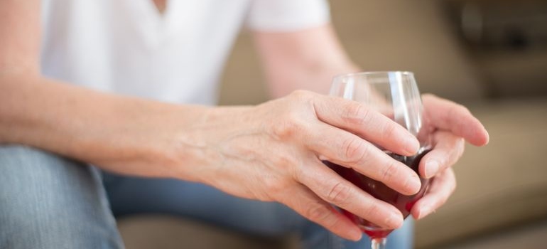 Older woman holding a glass of wine.