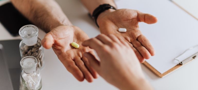 Doctor offering two pills to a patient.