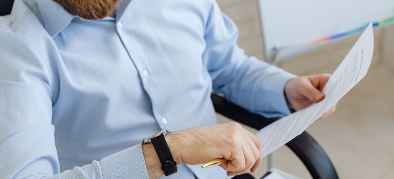 Man sitting in an office chair and reading a document.