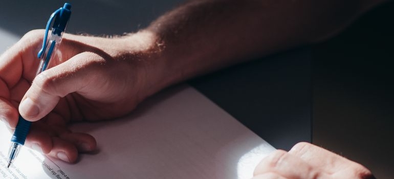 Man holding a pen while signing a document.