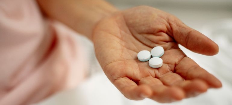 Person sitting in bed and holding sleeping pills in their palm.