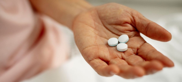 Person holding tablets in the palm of their hands.