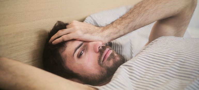 Man lying in bed and rubbing his eyes.