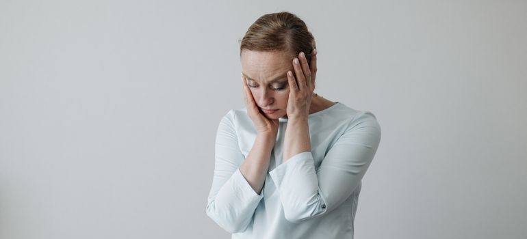 Woman holding her face while worrying about how long does lorazepam take to wear off.
