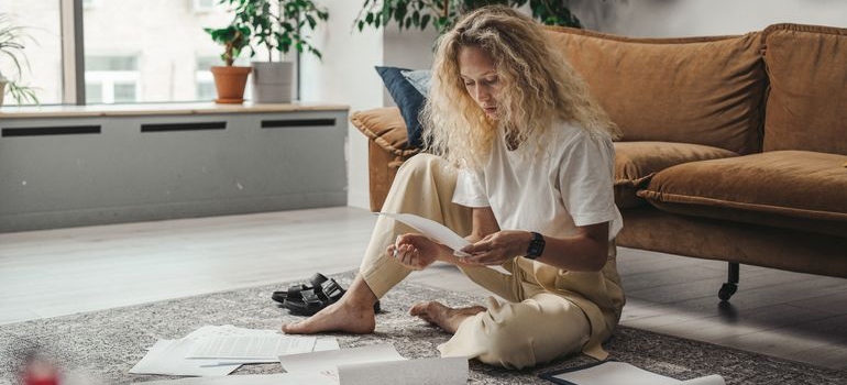 Woman sitting on the ground and reading documents.