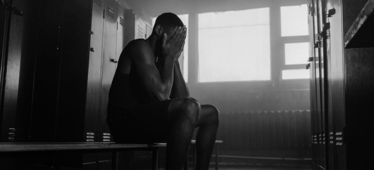 Man covering his eyes in the locker room.