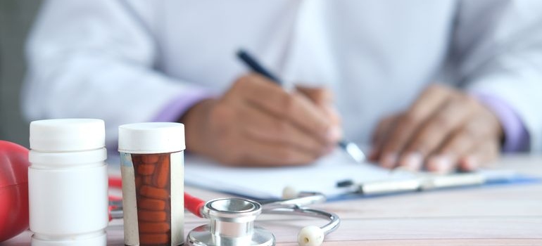 Doctor writing in a patient's chart while prescribing trazodone for sleep to a patient.