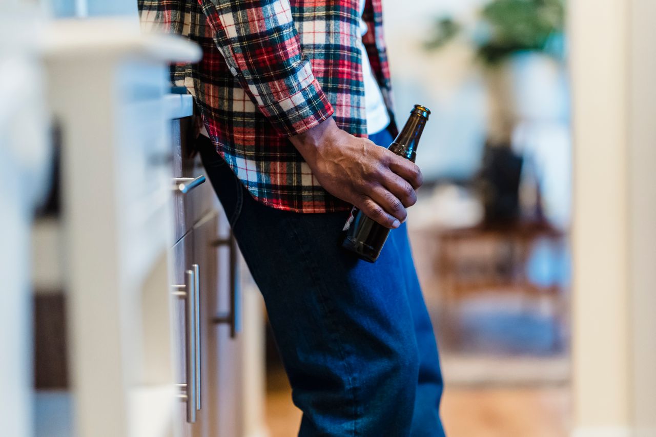 Man holding a bottle of beer after doing intermittent sobriety.